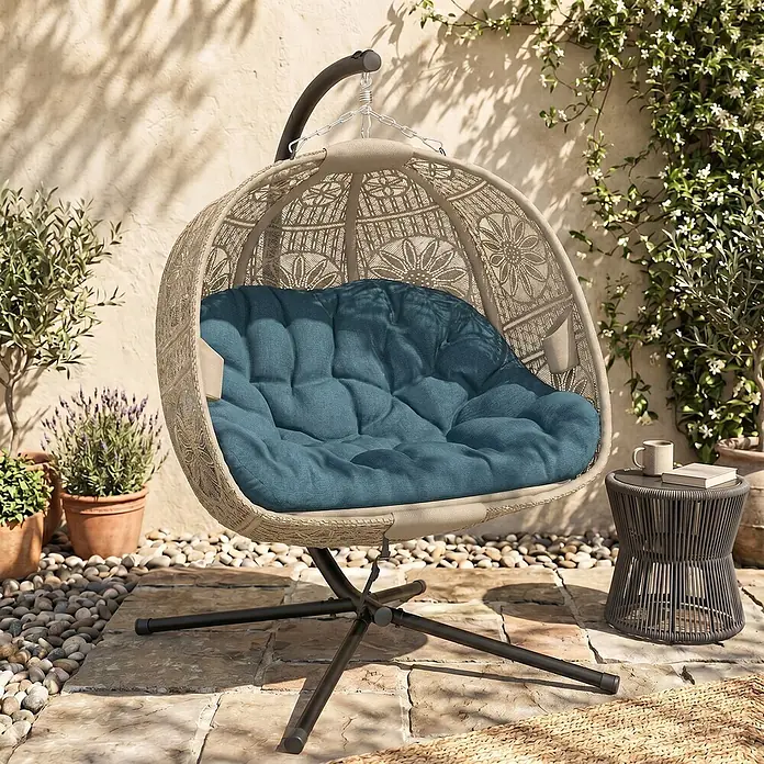 Furnicato Hängesessel - L x B x H: 132 x 126 x 172 cm, Stahl, Schwarz - Beiger geflochtener Eierstuhl mit blauem Kissen, an schwarzem Gestell auf sonniger Terrasse mit Pflanzen und Beistelltisch.