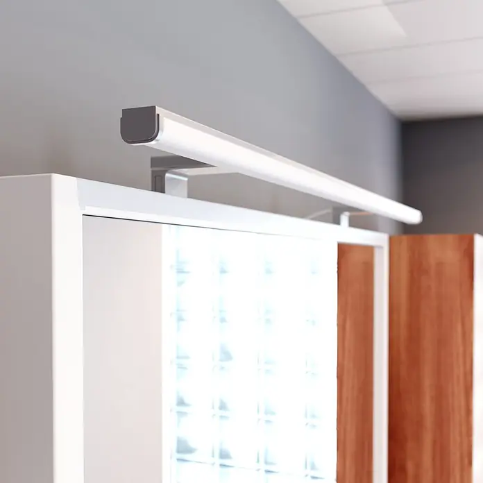 kalb LED Spiegelleuchte Lumenia 100cm 3000K Chrom 2in1 Montage -  - Lineare LED-Schrankleuchte, silber und weiß, über einem weißen Schrank mit Glasbausteinen montiert.