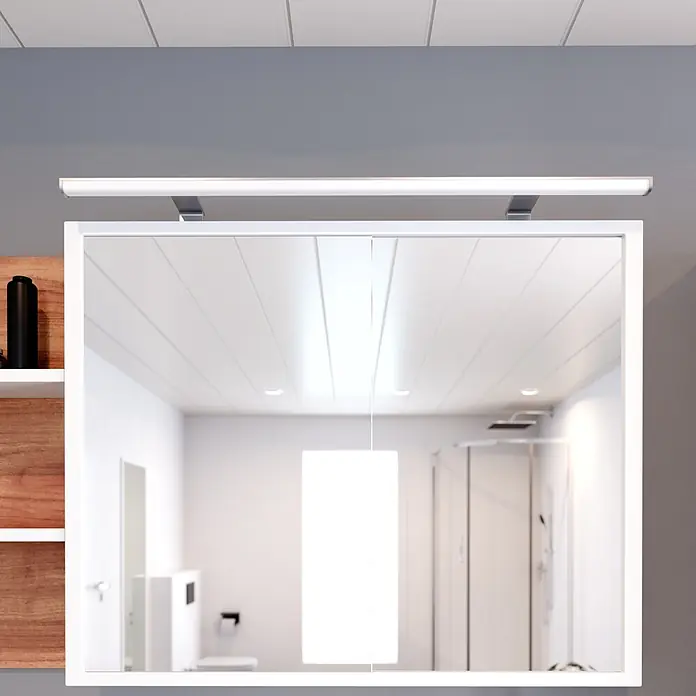 kalb LED Spiegelleuchte Lumenia 100cm 3000K Chrom 2in1 Montage -  - Weißer Spiegelschrank mit integrierter LED-Lichtleiste, spiegelt ein modernes Badezimmer mit Dusche und Toilette wider.