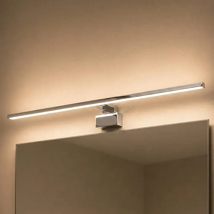 kalb LED Spiegelleuchte Running Light 100cm 3000K Chrom Lichtlauf -  - Schlanke Chrom-LED-Spiegelleuchte über einem Spiegel, warmes Licht abgebend.