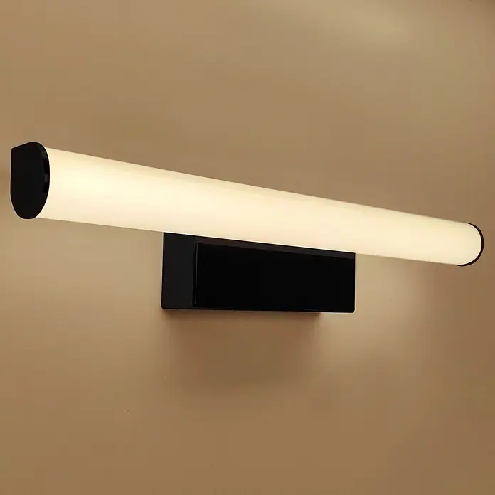 kalb LED Spiegelleuchte 30cm 4000K Schwarz Rund -  - Eine moderne, wandmontierte LED-Leuchte mit schwarzem Sockel und langem, leuchtendem, weißem Zylinderdiffusor an einer hellbraunen Wand.