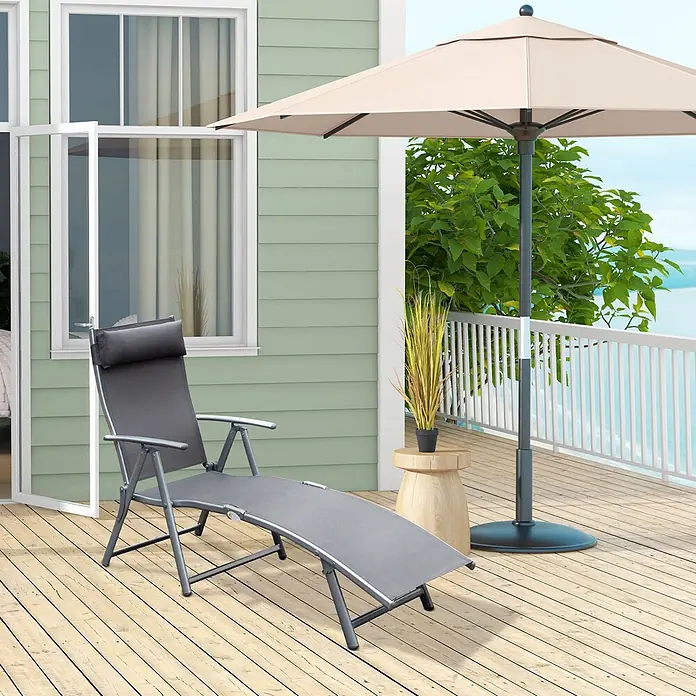 SONNENH Gartenliege - B x T: 137 x 63,5 cm, Grau, Metall, Klappbar - Ein grauer klappbarer Outdoor-Liegestuhl mit Kopfkissen steht auf einer Holzterrasse, bereit zur Entspannung unter einem beigen Sonnenschirm.