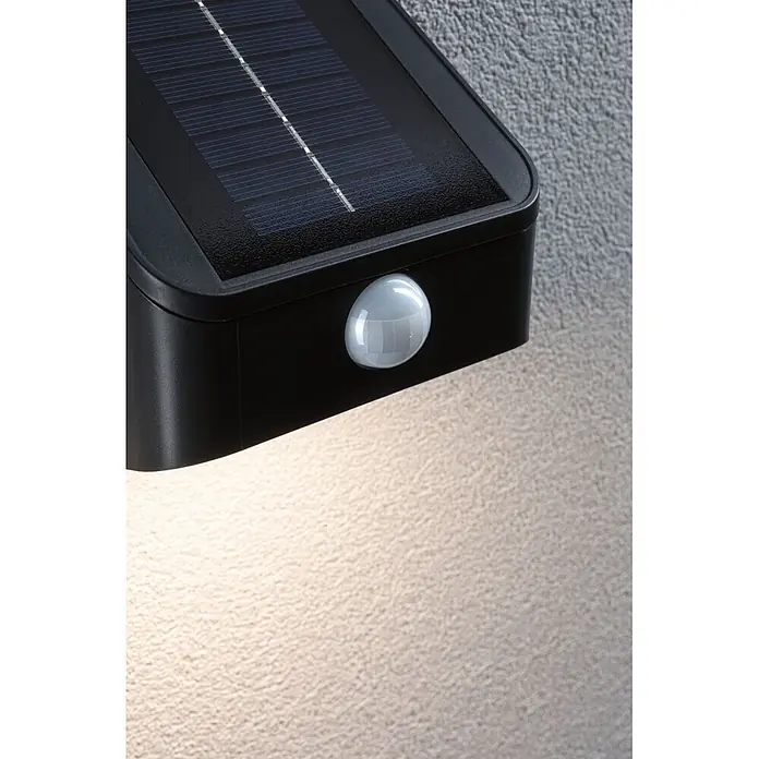 Paulmann Solarleuchte Lesly - Lichtfarbe: Warmweiß, LED, Höhe: 138 mm - Schwarze Solar-Wandleuchte mit Solarmodul und weißem Bewegungssensor, beleuchtet eine strukturierte Wand.