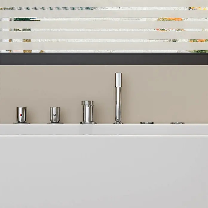Home Deluxe Eckbadewanne AMBER inkl. Whirlpool-Funktion - Weiß - Verchromte Badarmatur mit Auslauf, Handbrause und zwei Bedienknöpfen, auf einem weißen Badewannenrand montiert.