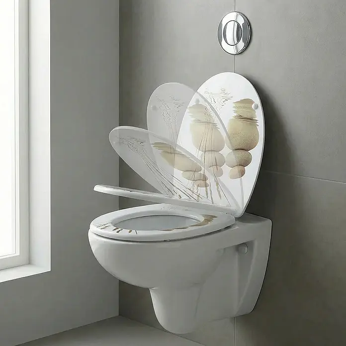 SAINOS WC-Sitz MDF WC-Sitz, Universal-O-Form, Absenkautomatik, Unten - MDF, Beige, Mit Absenkautomatik - Wandhängendes weißes WC mit dekorativem Sitz und Deckel, verziert mit gestapelten Steinen und Schilf. Der Deckel ist teilweise geöffnet.