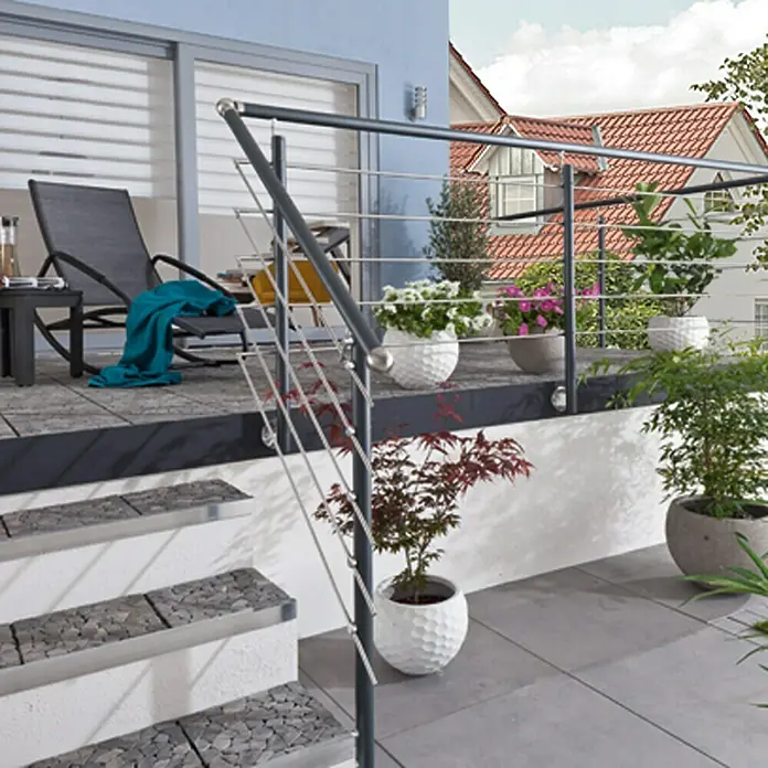 Treba Frewa Geländer-Set AG5 - Seitenmontage, Aluminium, Anthrazit, Edelstahl, Länge: 150 cm - Bild einer Außentreppe mit Edelstahlgeländer, die zu einer Terrasse mit Möbeln und Pflanzen führt.