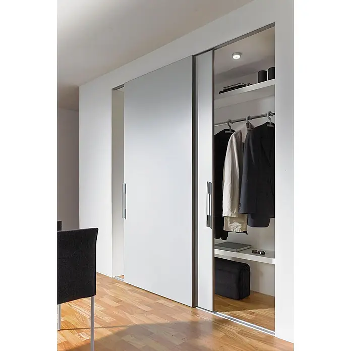 Hettich Montage-Set SlideLine 16 - Passend für: 1 Schiebetür, Traglast: 60 kg - Weißer Schwebetürenschrank mit Chromgriffen, teilweise geöffnet, zeigt Kleidung und Regale in einem Raum mit Holzboden.