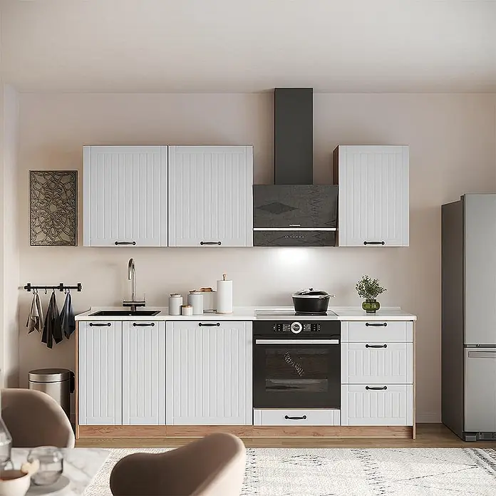 Vicco Küchenzeile - Breite: 230 cm, Weiß Landhaus, Ohne Elektrogeräte - Moderne Küche mit weißen geriffelten Schränken, heller Arbeitsplatte, schwarzen Griffen, integrierten schwarzen Geräten und einem grauen Kühlschrank.