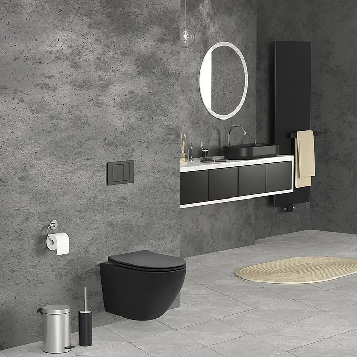 LuxeBath Wand-WC ohne Spülrand Schwarz, Tornadospülung, Softclose-Klodeckel - Schwarz - Modernes Bad mit schwarzem Wand-WC, Waschtisch mit schwarzem Waschbecken, rundem Spiegel und schwarzem Handtuchwärmer vor Betonwänden.
