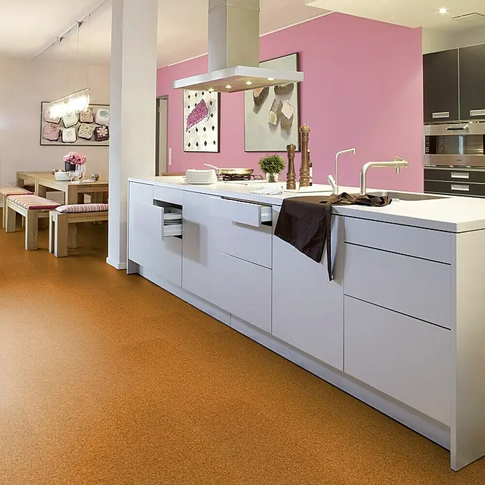 Corklife Studiostyle Korkboden - Beja, 905 x 295 x 10,5 mm - Helle Küche mit einer Kücheninsel in Weiß, einem Kochfeld, Spüle und einer Ablufthaube. Im Hintergrund ist eine pinkfarbene Wand zu sehen.