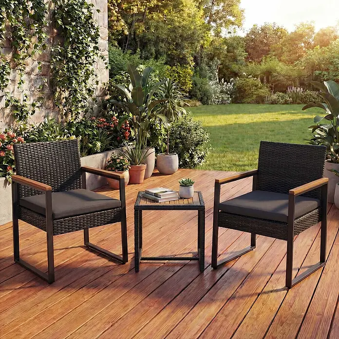 Mendler Loungemöbel-Set HWC-P74 - 3 -tlg., Polyrattan, Schwarz, Polster grau, Schwarz, grau - Gartensitzgruppe mit zwei schwarzen Korbstühlen mit grauen Kissen und Holzarmlehnen sowie einem schwarzen Metall-Beistelltisch auf einer Holzterrasse.