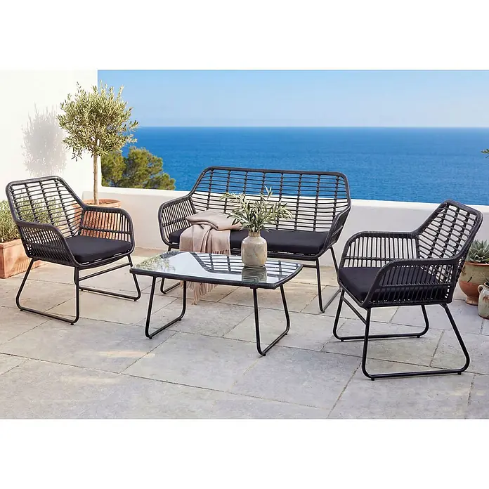 Mendler Loungemöbel-Set HWC-G17 - 4 -tlg., Polyrattan, Anthrazit, Polster anthrazit ohne Dekokissen, Anthrazit, Polster anthrazit - Schwarze Rattan-Loungegruppe mit zwei Sesseln, Zweiersofa, Glastisch und schwarzen Kissen auf Terrasse am Meer.