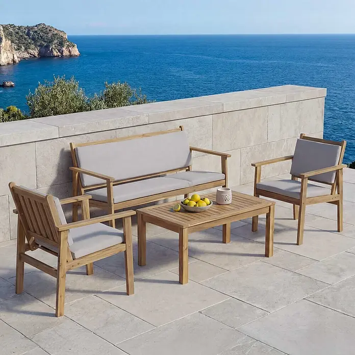 Mendler Loungemöbel-Set HWC-O19 - 4 -tlg., Holz, Kissen grau, Grau - Gartenmöbel-Set aus Holz mit hellgrauen Polstern, bestehend aus Sofa, zwei Stühlen und einem Couchtisch, auf einer Terrasse mit Meerblick.