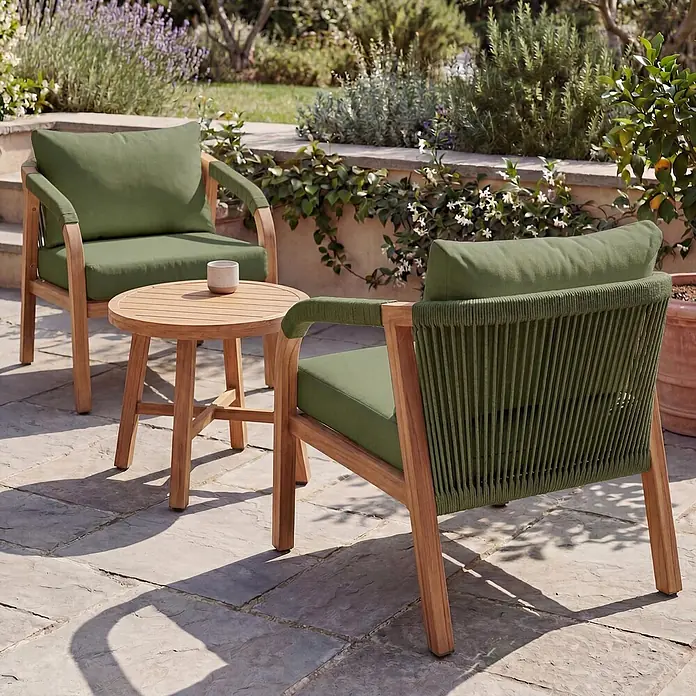 Mendler Loungemöbel-Set HWC-P82 - 3 -tlg., Metall, Holz-Optik olivgrün, Holz-Optik olivgrün - Zwei helle Outdoor-Sessel aus Holz mit grünen Kissen, einer mit geflochtenem Seildetail, und ein runder Holznebentisch auf einer Terrasse.