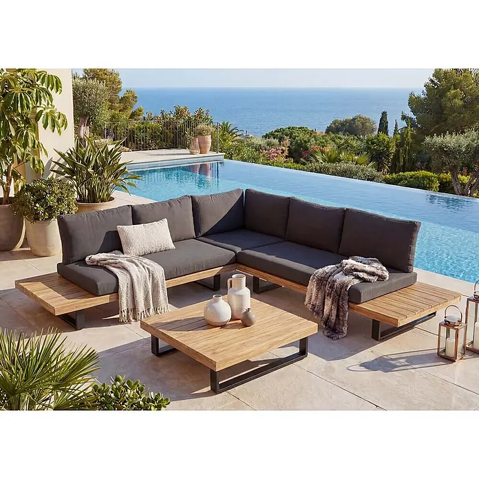 Mendler Garten-Garnitur HWC-H54 Akazie Alu - Hellbraun, Polster dunkelgrau -  - Eine L-förmige Outdoor-Lounge-Gruppe mit dunkelgrauen Kissen und Holzrahmen, dazu ein passender Couchtisch auf einer Terrasse am Pool.