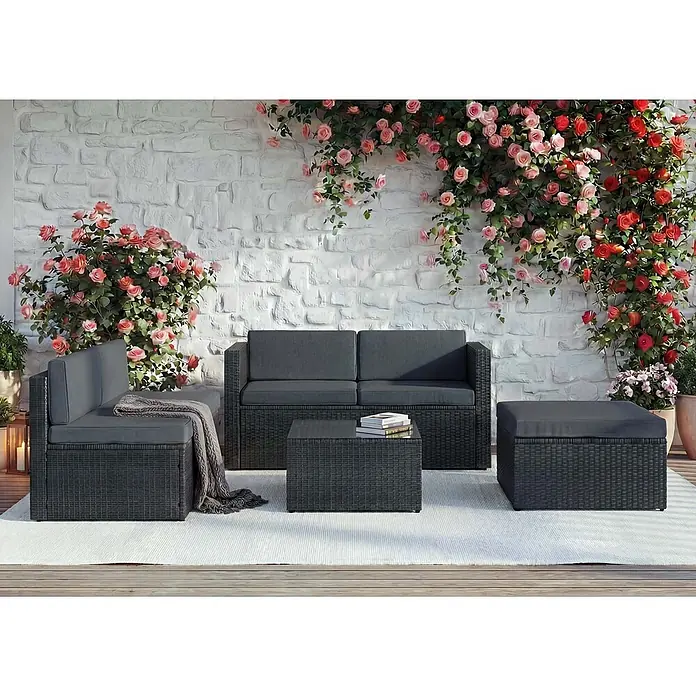 Mendler Poly-Rattan-Garnitur HWC-D24 - anthrazit, Polster dunkelgrau -  - Dunkelgraue Rattan-Gartenlounge mit Sofas, Couchtisch und Hocker auf einer Terrasse mit Rosen.