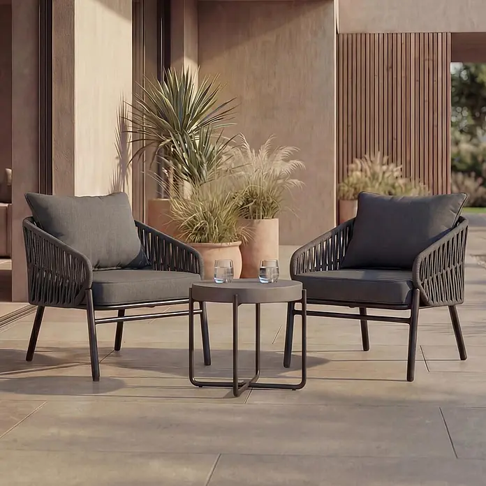 Mendler Gartensessel HWC-P90 - 1 Stk., Metall, Anthrazit, B x T x H: 64 x 70 x 67 cm - Ein dunkelgraues Outdoor-Lounge-Set mit zwei geflochtenen Stühlen und einem runden Beistelltisch auf einer Terrasse.