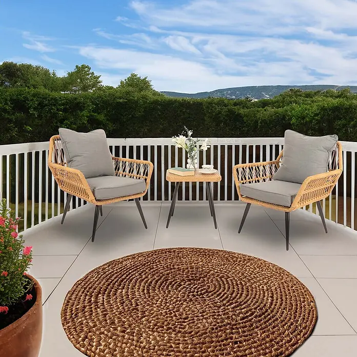 Mendler Poly-Rattan Garnitur HWC-N34 - dunkelgrau -  - Runder brauner geflochtener Teppich auf einem Balkon mit Gartenmöbeln.