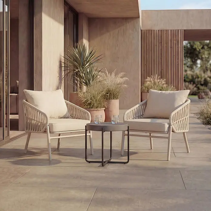 Mendler Gartensessel HWC-P90 - 1 Stk., Metall, Creme, B x T x H: 64 x 70 x 67 cm - Zwei helle geflochtene Outdoor-Sessel mit einem dunkelgrauen Beistelltisch auf einer Terrasse.