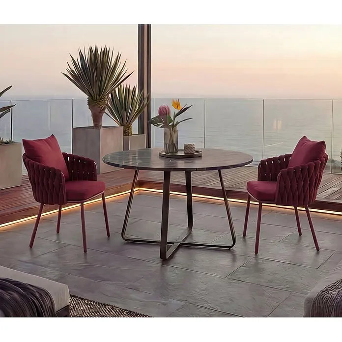 Mendler Gartenstuhl-Set HWC-P89 - 2 Stk., Metall, Bordeaux, B x T x H: 56 x 57 x 71 cm - Eine Outdoor-Essgruppe mit rundem dunklem Tisch und zwei roten Samtsesseln auf einem Balkon mit Meerblick bei Sonnenuntergang.