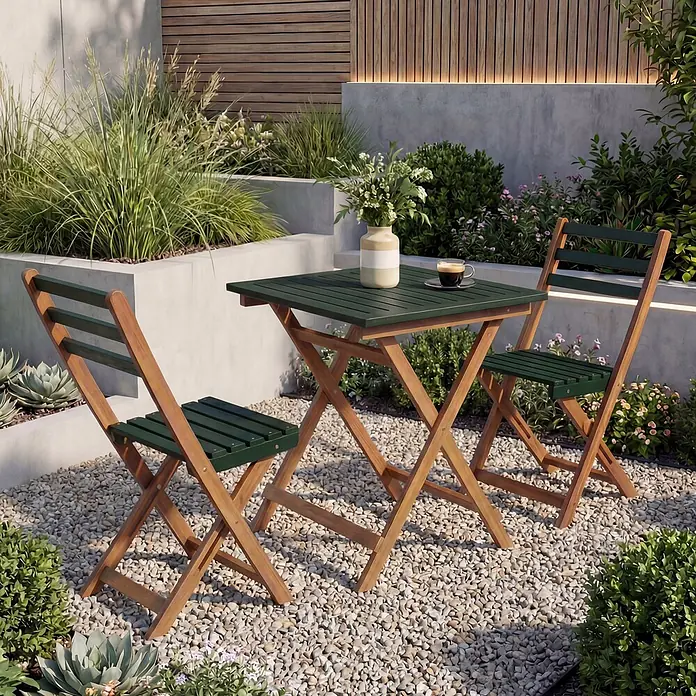Mendler Garnitur HWC-P71 Akazie Holz klappbar - Natur-grün -  - Eine klappbare Bistro-Garnitur aus Holz und Grün, bestehend aus Tisch und zwei Stühlen, steht auf einem Kiesweg im Garten.