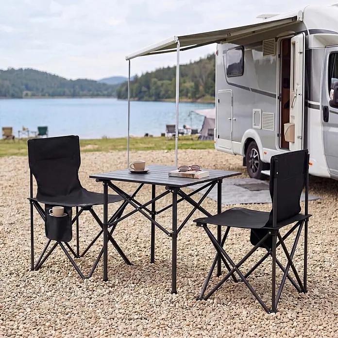 Mendler Gartenmöbel-Set HWC-Q39 - 3 -tlg., Textil, Schwarz, Schwarz - Schwarzer Campingtisch und zwei Stühle vor einem See mit Wohnmobil, ideal für Reisen und Entspannung im Freien.