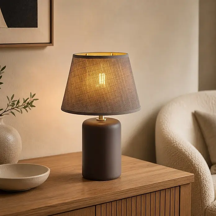 Home Sweet Home Lampenschirm Melrose - Ø x H: 20 x 13 cm, Hellgrau, Stoff, Rund - Eine dunkelbraune Tischlampe mit grauem Textillampenschirm steht auf einem Holzschrank und spendet warmes Licht in einem gemütlichen Raum.