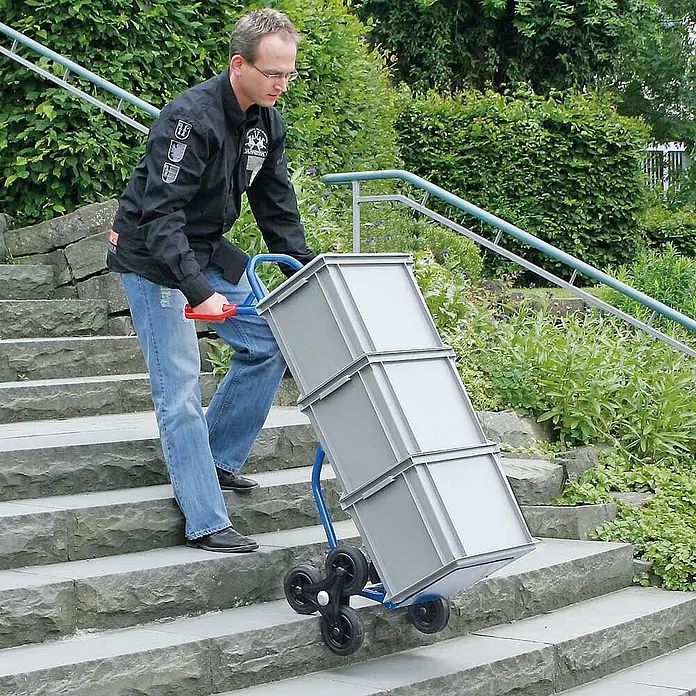 BRB Treppen-Sackkarre - Stahl - Blaue Treppenkarre mit Sternradsystem transportiert graue Kisten eine Außentreppe hinauf.