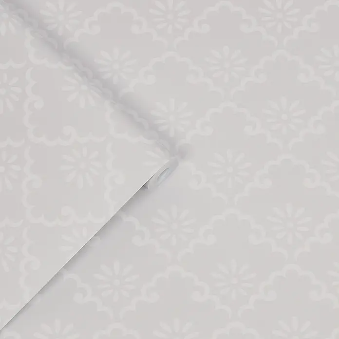 Vliestapete Laura Ashley Coralie  1000x52cm -  - Hellgraue Tapete mit subtilem weißen Blumen- und Wolkenmuster, teilweise abgerollt.