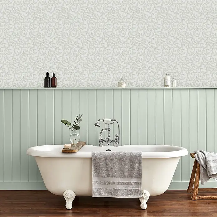 Vliestapete Laura Ashley Erwood  1000x52cm -  - Hellgrüne Tapete mit Blattmuster ziert eine Badezimmerwand über dekorativer Vertäfelung.
