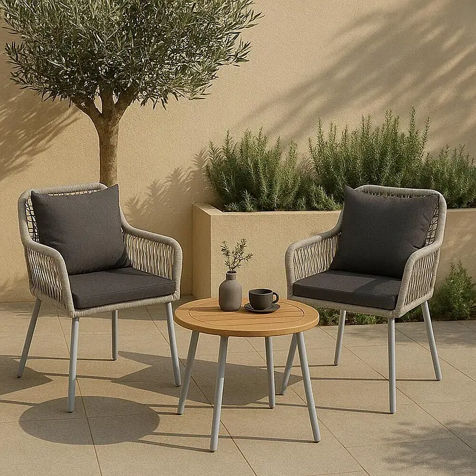 Mendler 2x Gartenstuhl HWC-O12 Rückenpolster - grau, Bezug dunkelgrau -  - Outdoor-Bistro-Set mit zwei hellgrauen Geflechtsesseln mit dunklen Kissen und einem runden Holztisch mit hellgrauen Beinen.