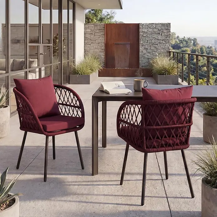 Mendler 2er-Set Gartenstuhl HWC-Q38 - Gestell schwarz, Polster Bordeaux -  - Zwei bordeauxrote geflochtene Outdoor-Stühle mit Kissen auf einer Terrasse, neben einem Tisch mit Buch und Tasse.
