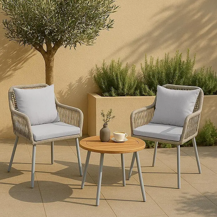 Mendler 2x Gartenstuhl HWC-O12 Rückenpolster - grau, Bezug grau -  - Eine Outdoor-Sitzgruppe mit zwei geflochtenen Sesseln mit hellgrauen Kissen und einem runden Holztisch auf einer Terrasse.