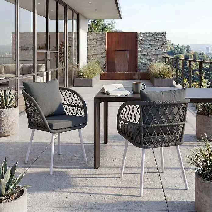 Mendler 2er-Set Gartenstuhl HWC-Q38 - Gestell hellgrau, Polster anthrazit -  - Zwei dunkelgraue Outdoor-Stühle aus geflochtenem Seil mit weißen Beinen und grauen Kissen auf einer Terrasse mit Tisch.