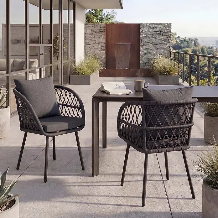 Mendler 2er-Set Gartenstuhl HWC-Q38 - Gestell schwarz, Polster anthrazit -  - Zwei dunkelgraue Gartenstühle aus geflochtenem Seil mit Kissen stehen an einem Outdoor-Tisch auf einem modernen Balkon.
