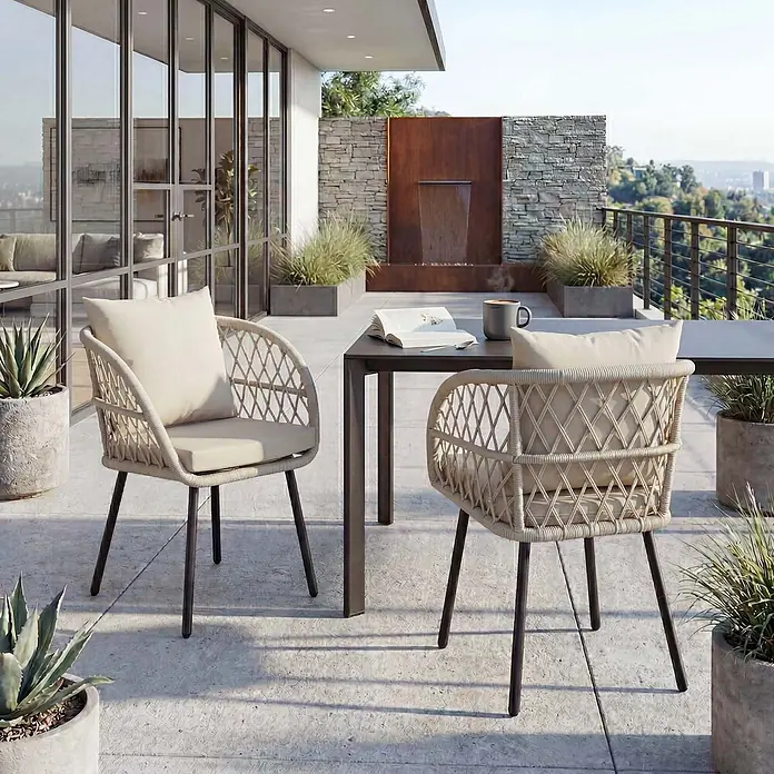 Mendler 2er-Set Gartenstuhl HWC-Q38 - Gestell schwarz, Polster Creme -  - Zwei beigefarbene geflochtene Outdoor-Stühle mit Kissen an einem dunklen rechteckigen Tisch auf einer Terrasse.