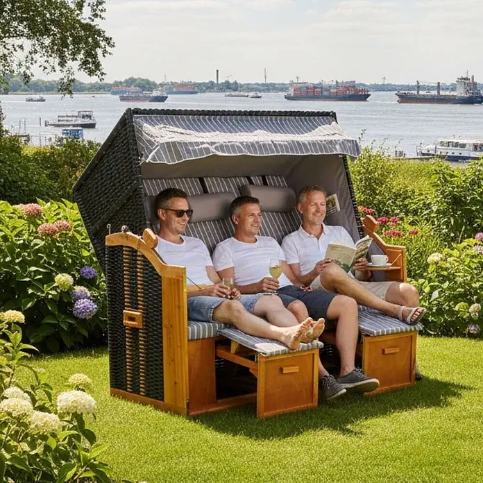 Strandkorb Ostsee XXL Wacholder PE Schwarz Dessin Royal Grau -  - Dunkler Strandkorb aus Korbgeflecht und Holz mit gestreiften Kissen, drei Männer entspannen im Freien.