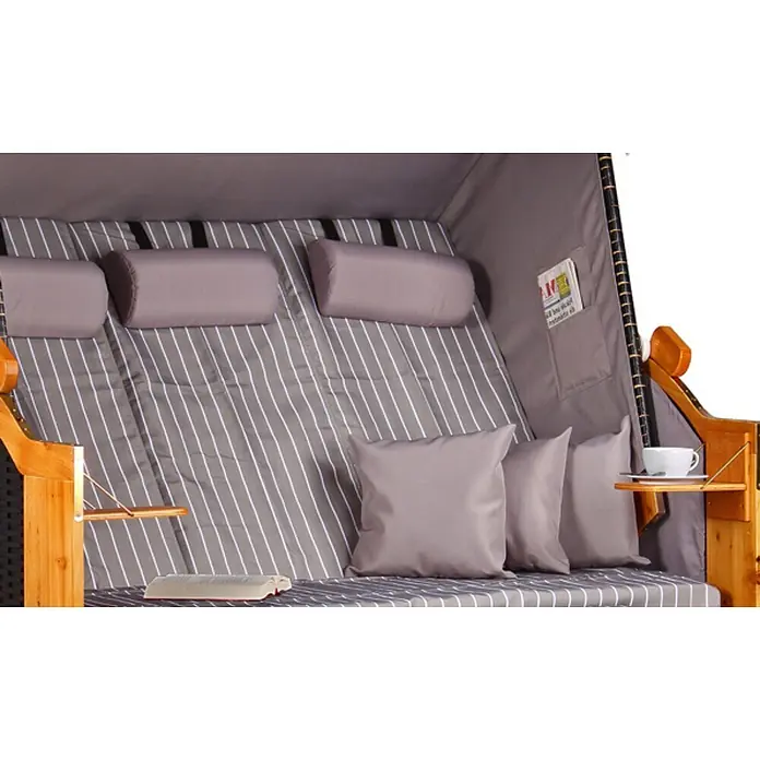 Strandkorb Ostsee XXL Wacholder PE Schwarz Dessin Royal Grau -  - Komfortabler Strandkorb innen mit grau-gestreiftem Stoff, passenden Kissen, Holzarmlehnen und Beistelltischen mit Buch und Tasse.
