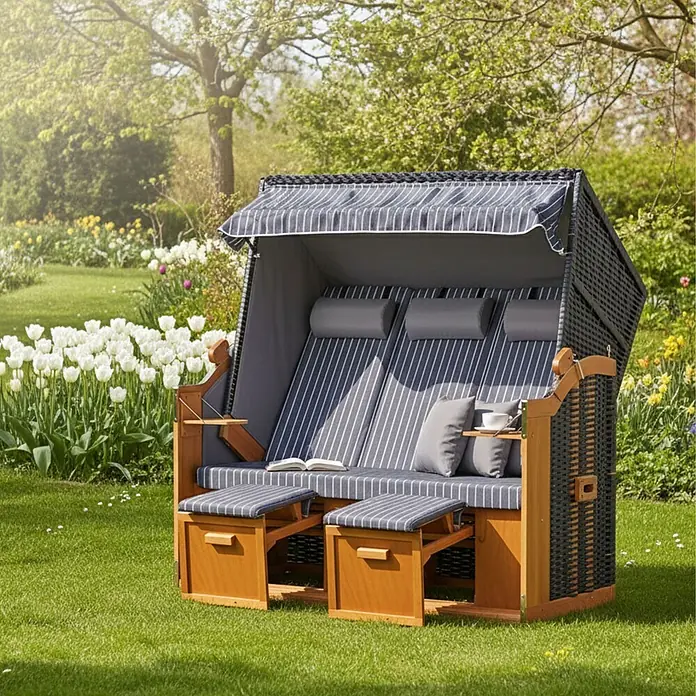 Strandkorb Ostsee XXL Wacholder PE Schwarz Dessin Royal Anthrazit -  - Doppelstrandkorb aus Holz und dunklem Geflecht mit gestreiften grauen Kissen in einem sonnigen Garten mit weißen Tulpen.