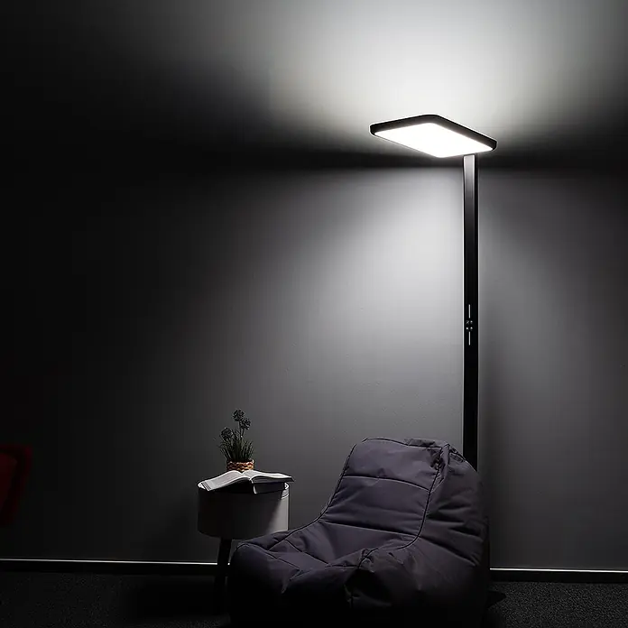 LUXULA LED Stehleuchte 100 W 4000 K neutralweiß schwarz dimmbar -  - Eine moderne schwarze LED-Stehlampe beleuchtet einen dunkelgrauen Sitzsack und einen Beistelltisch mit Buch für eine gemütliche Leseecke.