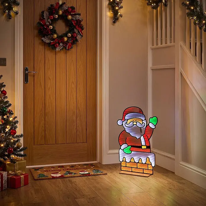 ECD Germany LED-Weihnachtsdekofigur Weihnachtsmann 3D Spiegel Lichterkette mit Timer 38x60 cm - 38 x 15 x 60 cm, Bunt, LED - Beleuchtete Weihnachtsmann-Dekoration in einem Flur, mit einem Weihnachtsmann auf einem Schornstein mit LED-Lichtern in verschiedenen Farben.
