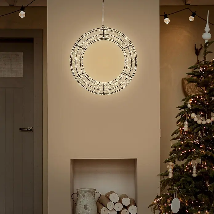 ECD Germany LED Weihnachtskranz Ø38 cm mit Lichterkette 480 LEDs -  - Ein beleuchteter runder Kranz mit dunklem Metallrahmen und warmweißen LEDs, der in einem festlichen Raum an einer Wand hängt.
