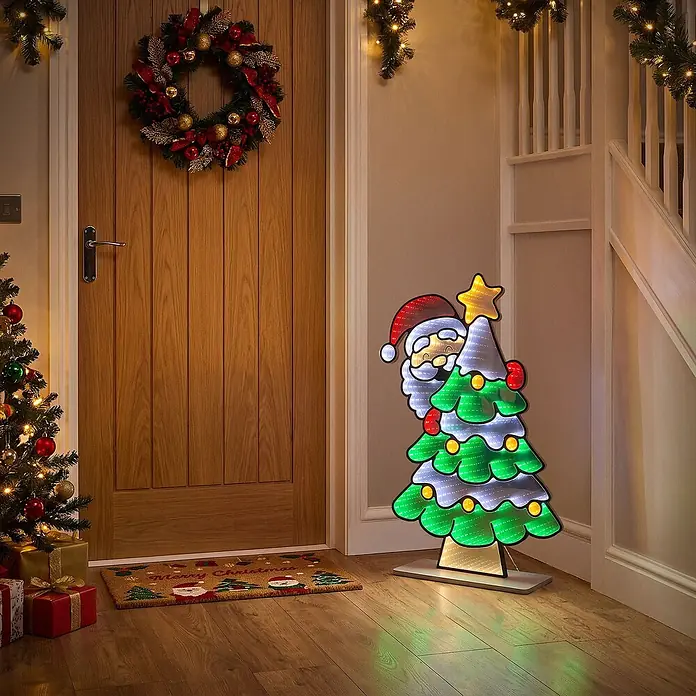 ECD Germany Weihnachtsdeko Weihnachtsbaum LED Infinity Mirror 3D-Effekt -  - Ein festliches beleuchtetes LED-Display mit Weihnachtsmann und Weihnachtsbaum steht in einem warm beleuchteten Flur und verleiht der Weihnachtsdekoration einen fröhlichen Glanz.