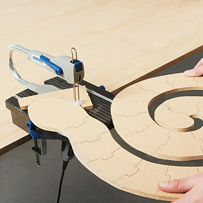 Dremel Moto-Saw Allzweck-Holzsägeblatt MS 51 - Passend für: Dremel Moto-Saw, Länge: 100 mm - Dremel Moto-Saw beim Schneiden eines Holzpuzzles, das handwerkliche Präzision und Vielseitigkeit des Werkzeugs demonstriert.