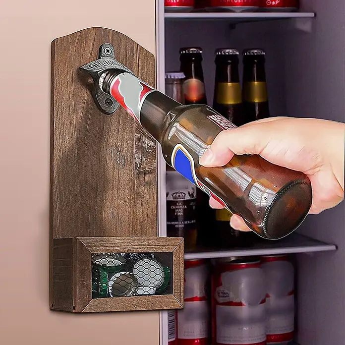 SONNENH Flaschenöffner - Holz - Rustikaler Wandflaschenöffner aus dunklem Holz mit Metallöffner und Kapselauffangnetz. Eine Hand öffnet eine Bierflasche, Kronkorken sind im Netz sichtbar.