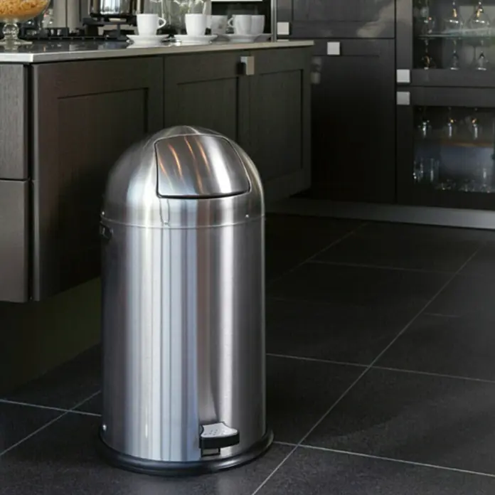 Vepa Bins Treteimer Kickcan - 33 l, Metall, Silber Metallic - Ein moderner, runder Edelstahl-Treteimer mit Deckel steht in einer stilvollen Küche mit dunklen Fliesen und passenden Schränken.