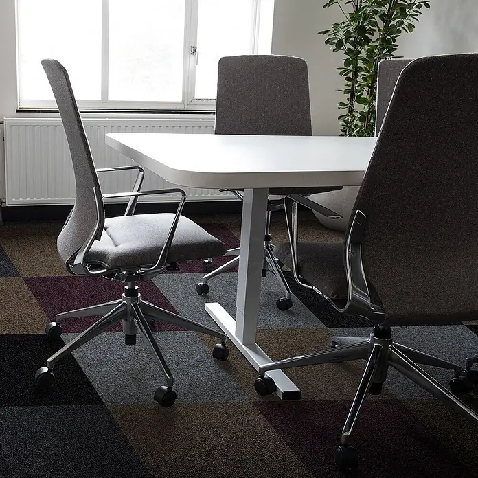 Floordirekt Teppichfliese Basel - 50 x 50 cm - 0,25 m² - Grün -  - Moderne graue Bürostühle mit Chromgestellen um einen weißen Besprechungstisch auf gemustertem Teppich.