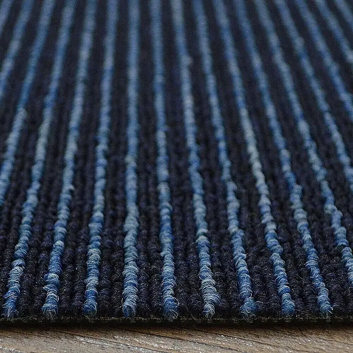 Floordirekt Teppichfliese Bohemia - 50 x 50 cm - 0,25 m² - Dunkelblau -  - Nahaufnahme eines dunkelblauen Teppichs mit hellblauen vertikalen Streifen und Schlingen, auf Holzfußboden.