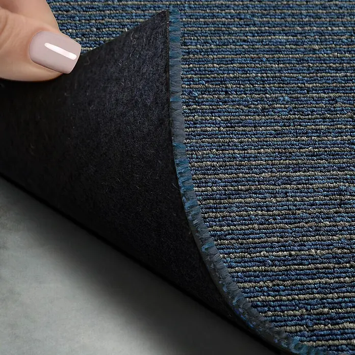 Floordirekt Teppichfliese Bohemia - 50 x 50 cm - 0,25 m² - Blau -  - Blau-grau gestreifter Teppich mit schwarzer Filzrückseite, Ecke angehoben, um den Boden zu zeigen.