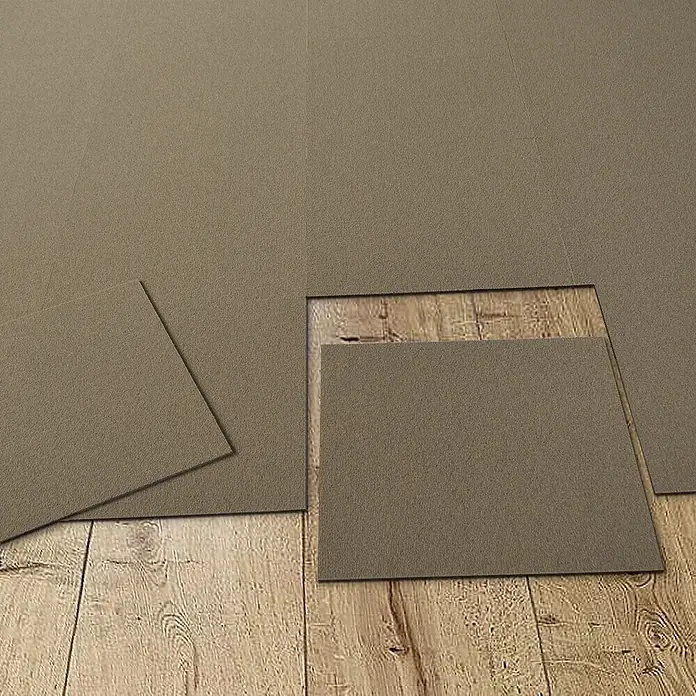 Floordirekt Teppichfliese Lyonn - 50 x 50 cm - 0,25 m² - Beige -  - Taupefarbene strukturierte quadratische Bodenfliesen bedecken teilweise einen Holzfußboden, einige Fliesen sind entfernt.